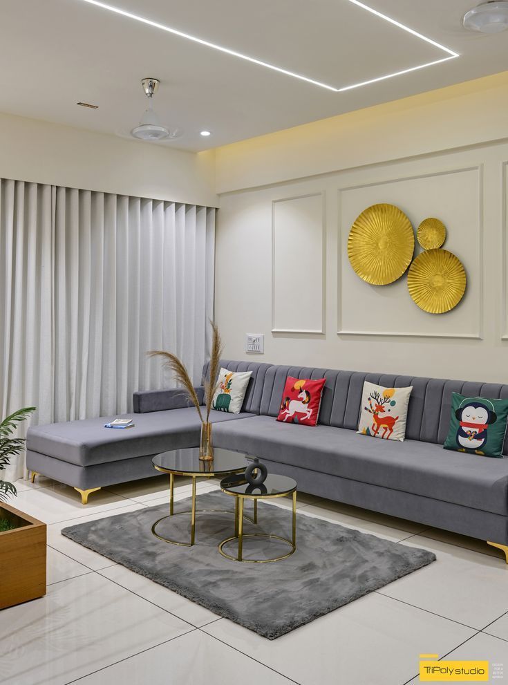 Grey sectional sofa arranged around nesting coffee tables under a linear ceiling light